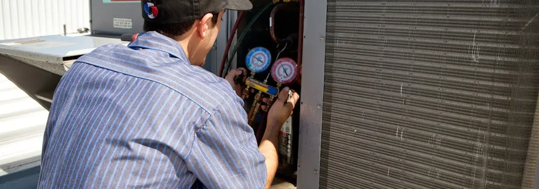HVAC technician servicing a condenser unit in Taneytown